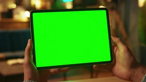 Close Up Hands Man Holding Tapping on Tablet Computer with Horizontal Green Screen Mock Up Dark Room