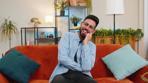 Smiling Man Laughing and Talking on Orange Couch