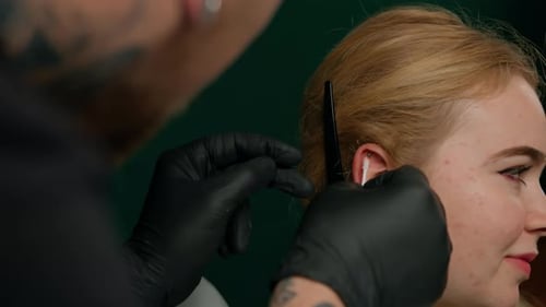 Piercing studio interior - piercing master makes a piercing to a girl, ear piercing