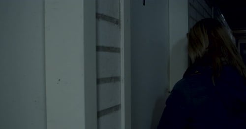 Woman in dark basement noticing a dark figure in the background