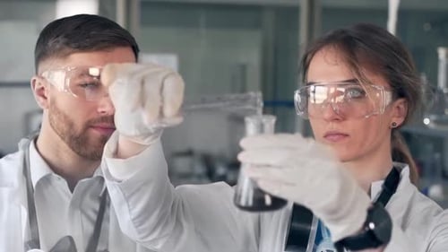 lab man and woman scientists in bathrobes are conducting a chemical experiment.
