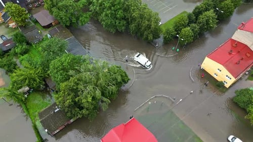 Flooded urban street with vehicles navigating through waterlogged roads and submerged areas