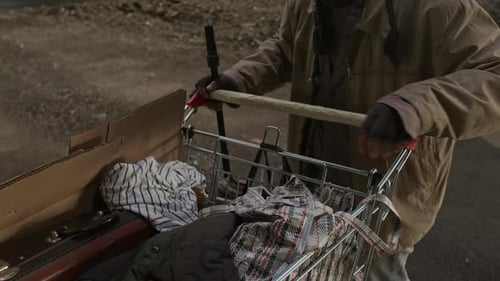 Man with cart organizing belongings at night