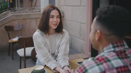 Multiethnic Couple in Love Holding Hands in Street Cafe The Guy and the Girl are Happy Together
