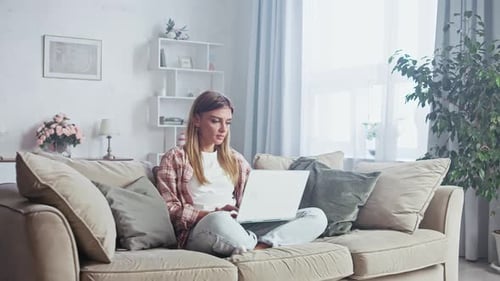 Woman Using Laptop on Couch in Living Room