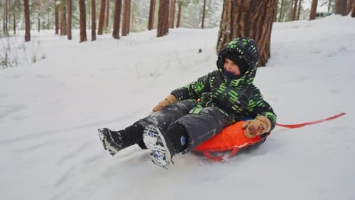 Kind genießt Winterrodeln im verschneiten Wald