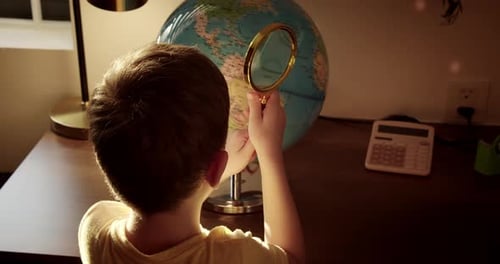 Young Boy Examines Globe with Magnifying Glass