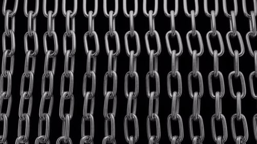 Chains falling in front of camera on green background. Unique link in chain.