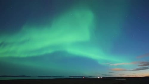 A beautiful dance of the northern lights in the night starry sky above the sea. A timelapse video.