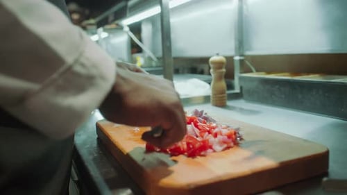 Black Chef Chopping Tomatoes and Red Onion on Wooden Board at Kitchen Table