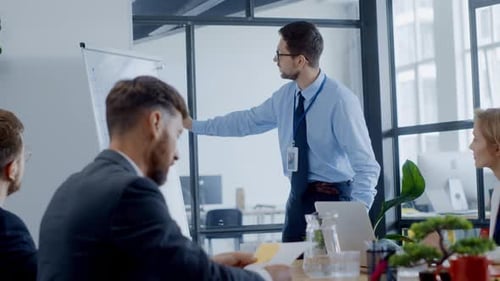A Man Gives a Presentation to a Group Gathered in an Office Setting