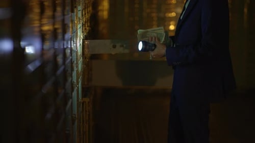 Man with Money Checks Safety Deposit Boxes at Night
