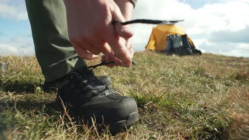 Person Tying Hiking Boots Laces in Grassy Field