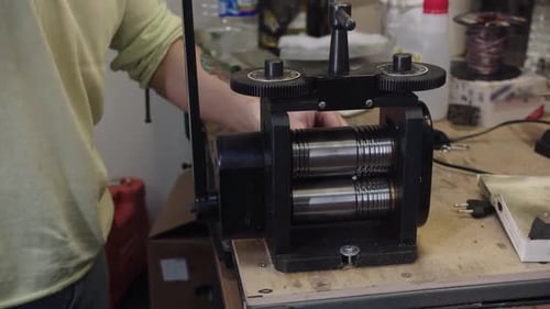 Person Uses Metal Rolling Mill in Workshop