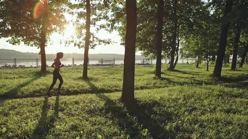 Athletic Woman Running Through Park on Sunny Day