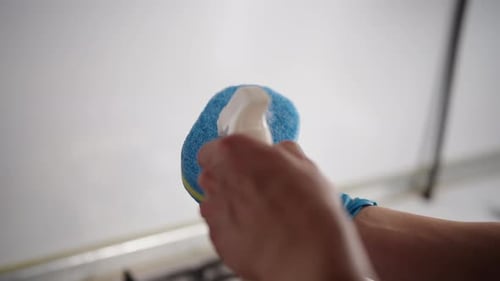 Hand Sprays Soapy Water onto Cleaning Sponge