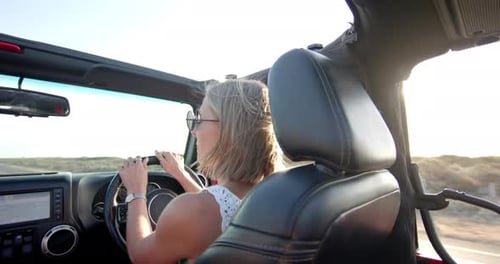 Junge kaukasische Frau genießt auf einem Roadtrip eine sonnige Fahrt in einem Cabrio