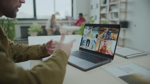 Man Video Conferencing with Business Team at Desk in Office