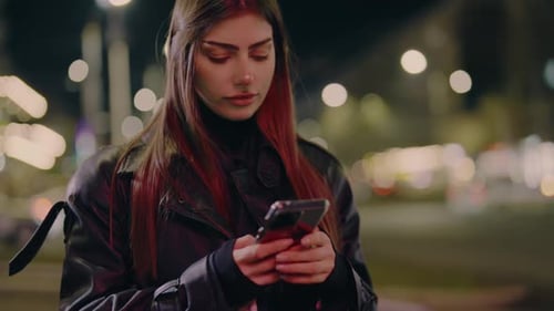 Closeup of a Woman Holding and Using Her Phone While Standing in the City