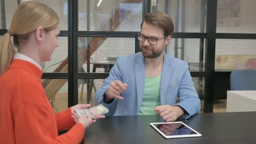 Man Giving Money to Woman in Office