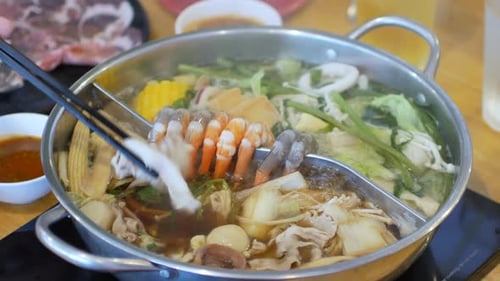 Vídeo 4K en punto de vista mientras se coloca carne de cerdo cortada en un shabu shabu shabu caliente lleno de verduras y carne.
Mapa