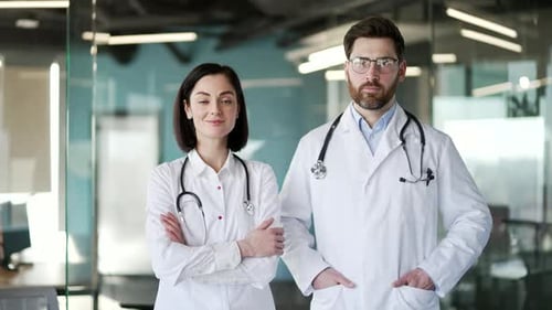Portrait of confident doctors man and woman standing in modern hospital clinic looking at camera.