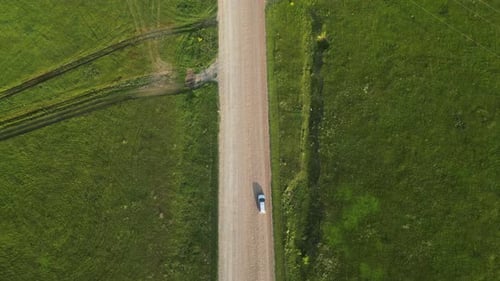 Rural Car Traversing Dirt Road Passing Through Lush Green Meadows Sunlight Illuminating Expansive