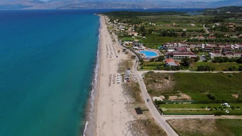 Aerial Drone Flies Along Sandy Beach with Turquoise Sea, Revealing Large Coastal Resort with Pool.