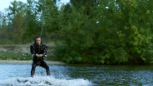 Wakeboarder Riding on Tranquil Water. Man on Wakeboard Without Enthusiasm on Face