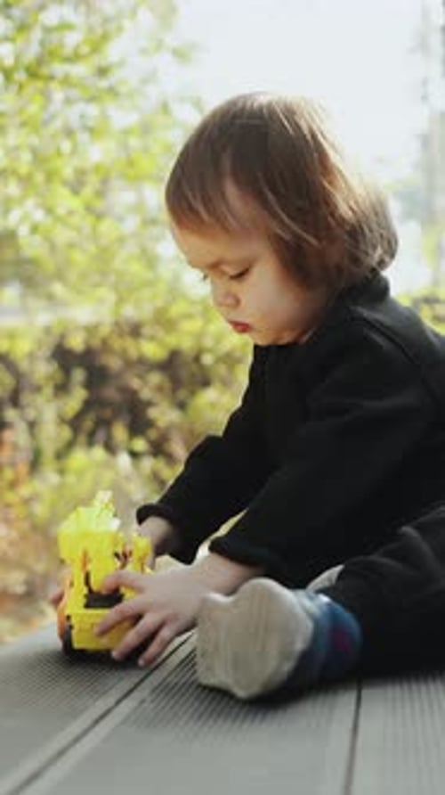 Child Playing with Toy Truck Outdoors