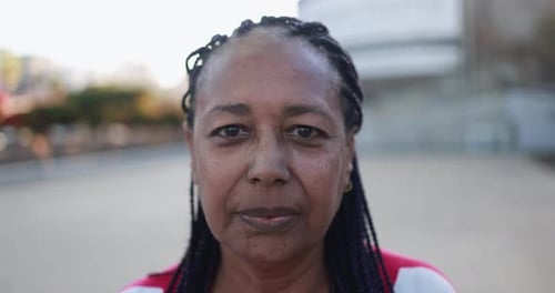 Mujer mayor africana mirando a la cámara con fondo de ciudad África