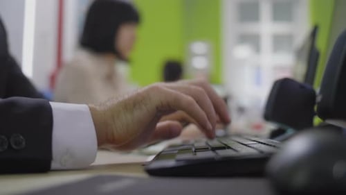 Typing on Keyboard in Office Environment. Close Up of Man's Hands Wearing a Suit.