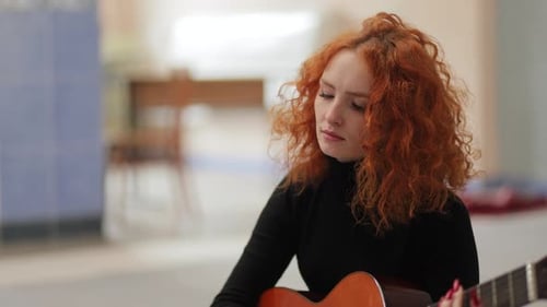 Young Woman Plays Guitar Indoors, Mid Shot