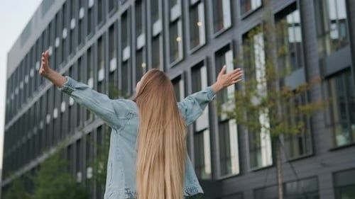 Happy Young Woman Spins Around Raising Arms High in Air