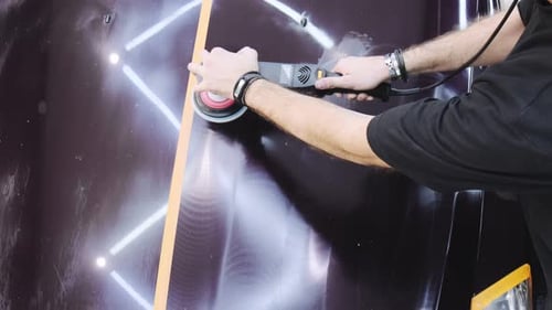 Car detailing. A man polishes the hood of a car with an orbital polisher. A beautiful wavy mark from