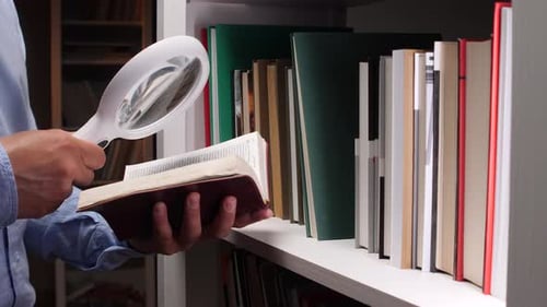 Chercheur lisant un livre à l'aide d'une loupe dans une bibliothèque