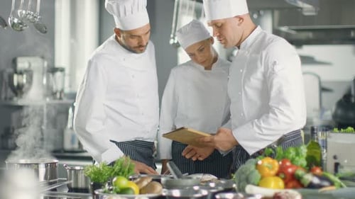 In der modernen Küche verwenden Köche den Tablet-Computer für Rezepte, sie lächeln und diskutieren