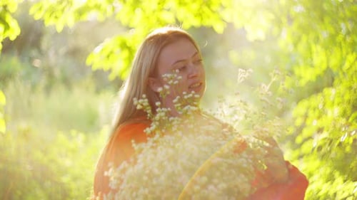 Woman Smiling with Wildflowers in a Green Meadow