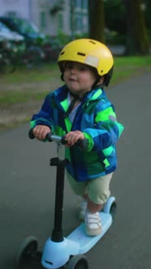 Toddler riding scooter fast in park wearing helmet smiling with excitement enjoying movement and