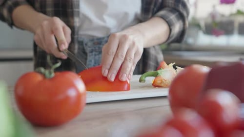 Woman Cuts Red Pepper in Kitchen