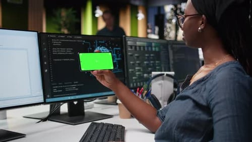 Teléfono con pantalla verde utilizado por una mujer en el lugar de trabajo de una empresa de tecnología