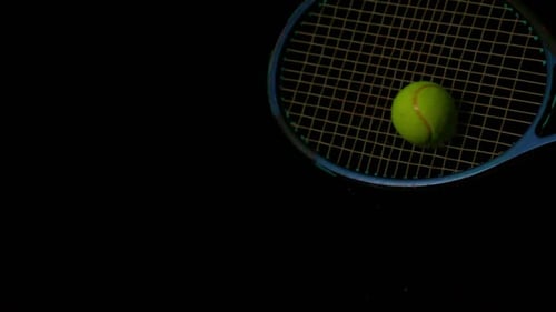 Tennis racket hitting a ball on black background