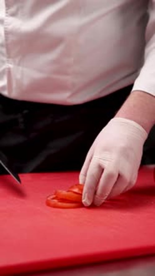 chef cuts tomatoes on a red cutting board