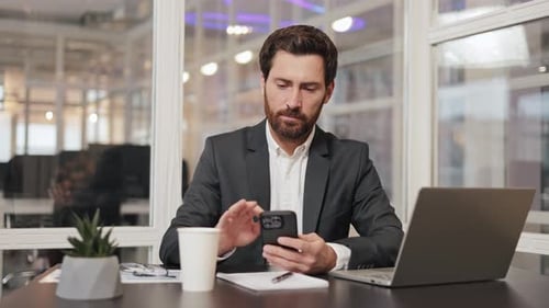 Businessman Working on Laptop and Phone in Office