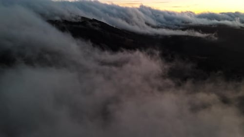 Aerial View of Majestic Mountain Peaks Shrouded in Clouds at Dusk