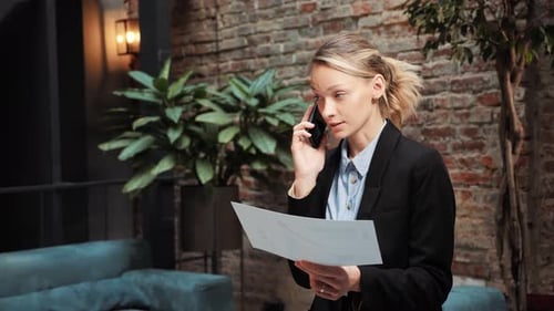 Business Woman Talking on Phone While Reviewing Report