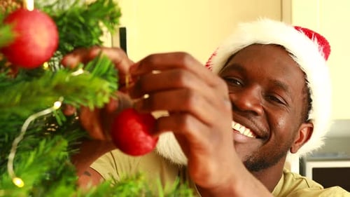 Man Decorating Christmas Tree Wearing Santa Hat