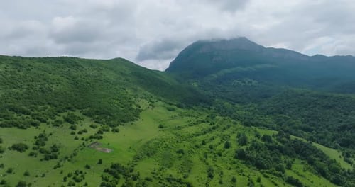 Belle pente verte avec de l'herbe et une forêt surplombant une incroyable formation rocheuse