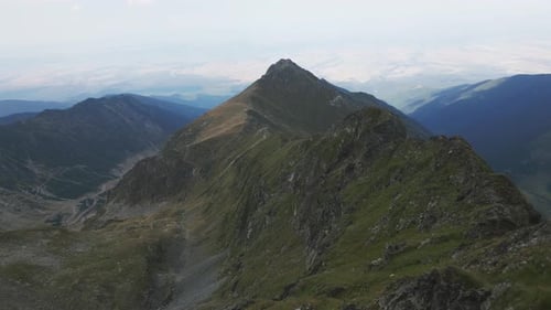 drone flies over a mountain ridge and reveals a big mountain and beautiful landscape in the backgrou