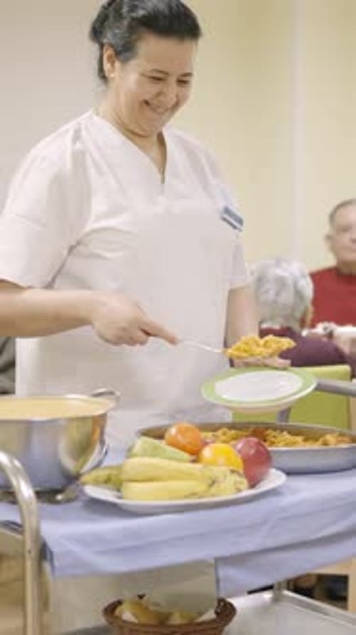 Friendly Cook Serving Food to Seniors in a Nursing Home